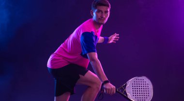 Raketli Padel tenisçi. Sahada raketli, neon renkli bir erkek sporcu. Spor konsepti. Bir spor uygulaması ya da bahis sitesi tasarımı için yüksek kaliteli bir fotoğraf indir