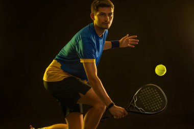 Raketli Padel tenisçi. Sahada raketli, neon renkli bir erkek sporcu. Spor konsepti. Bir spor uygulaması ya da bahis sitesi tasarımı için yüksek kaliteli bir fotoğraf indir