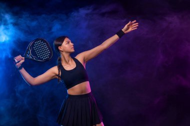 Raketli Padel tenisçi. Sahada raketi neon renkli genç bir sporcu kız. Spor konsepti. Bir spor uygulaması ya da bahis sitesi tasarımı için yüksek kaliteli bir fotoğraf indir