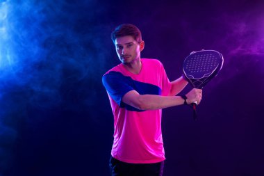 Raketli Padel tenisçi. Sahada raketli, neon renkli bir erkek sporcu. Spor konsepti. Bir spor uygulaması ya da bahis sitesi tasarımı için yüksek kaliteli bir fotoğraf indir