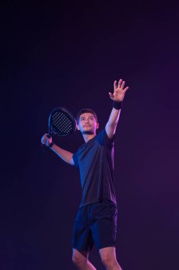 Raketli Padel tenisçi. Sahada raketli, neon renkli bir erkek sporcu. Spor konsepti. Bir spor uygulaması ya da bahis sitesi tasarımı için yüksek kaliteli bir fotoğraf indir