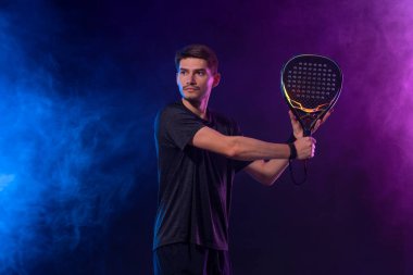 Raketli Padel tenisçi. Sahada raketli, neon renkli bir erkek sporcu. Spor konsepti. Bir spor uygulaması ya da bahis sitesi tasarımı için yüksek kaliteli bir fotoğraf indir