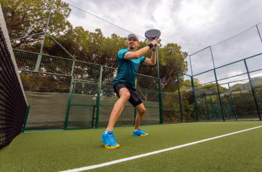 Saha arka planında Padel tenis oyuncusu var. Padel etkinlikleri için sosyal medya tanıtım şablonu. Turu aç.