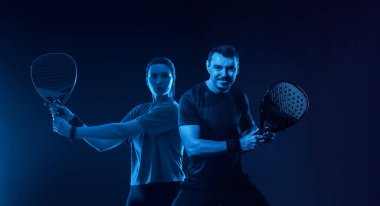 Raketli Padel tenis oyuncuları. Kız ve erkek sporcular kortta raketlerle raket oynuyorlar. Spor konsepti. Bir spor uygulaması ya da web sitesi tasarımı için yüksek kaliteli bir fotoğraf indir