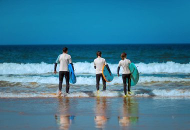 Okyanusta sörf yapmayı öğrenen bir sörfçü. İlk sörf dersi. Amatör sörfçü. Sörf eğitimi. Sosyal medyada sörf okulu reklamı için fotoğraf.