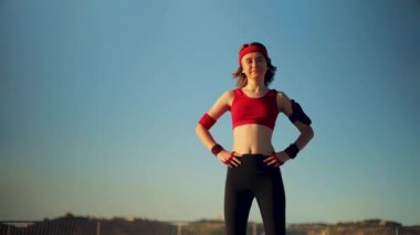 Genç kız, sabah yogasından sonra okyanus kıyısında poz veriyor. Sosyal ağ için motive edici bir fotoğraf. Kız sabahtan sonra dinleniyor, sette koşuyor. Fitness uygulaması için spor arkaplanı.