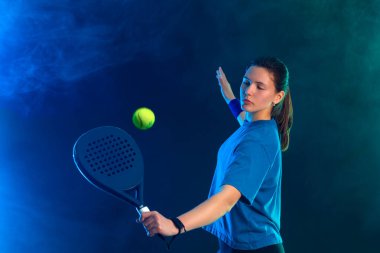 Raketli Padel tenisçi. Sahada raketi neon renkli genç bir sporcu kız. Spor konsepti. Bir spor uygulaması ya da bahis sitesi tasarımı için yüksek kaliteli bir fotoğraf indir