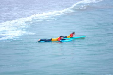 Okyanusta sörf yapmayı öğrenen bir sörfçü. İlk sörf dersi. Amatör sörfçü. Sörf eğitimi. Sosyal medyada sörf okulu reklamı için fotoğraf.