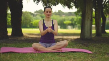 Yoga yapan bir kadın. Güzel kız çevrimiçi sınıfta Asana antrenmanı yapıyor. Sakinleş ve rahatla. Parkta yoga eğitimi almış.