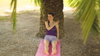 Yoga yapan bir kadın. Güzel kız çevrimiçi sınıfta Asana antrenmanı yapıyor. Sakinleş ve rahatla. Parkta yoga eğitimi almış.