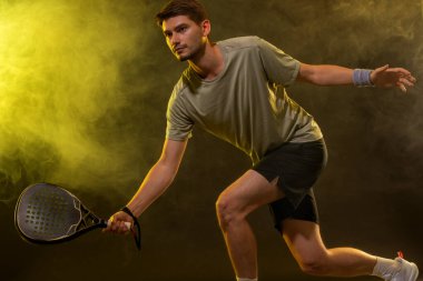 Raketli Padel tenisçi. Sahada raketli, neon renkli bir erkek sporcu. Spor konsepti. Bir spor uygulaması ya da bahis sitesi tasarımı için yüksek kaliteli bir fotoğraf indir