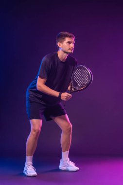 Raketli Padel tenisçi. Sahada raketli, neon renkli bir erkek sporcu. Spor konsepti. Bir spor uygulaması ya da bahis sitesi tasarımı için yüksek kaliteli bir fotoğraf indir