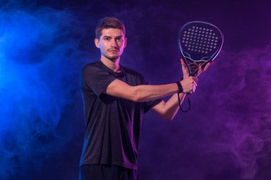 Raketli Padel tenisçi. Sahada raketli, neon renkli bir erkek sporcu. Spor konsepti. Bir spor uygulaması ya da bahis sitesi tasarımı için yüksek kaliteli bir fotoğraf indir