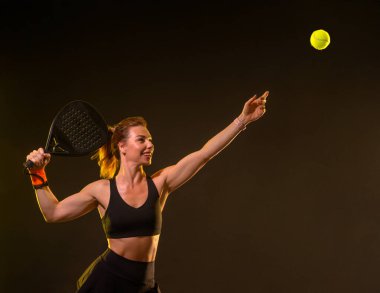 Raketli Padel tenisçi. Sahada raketi neon renkli genç bir sporcu kız. Spor konsepti. Bir spor uygulaması ya da bahis sitesi tasarımı için yüksek kaliteli bir fotoğraf indir
