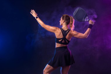 Raketli Padel tenisçi. Sahada raketi neon renkli genç bir sporcu kız. Spor konsepti. Bir spor uygulaması ya da bahis sitesi tasarımı için yüksek kaliteli bir fotoğraf indir