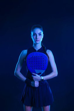 Raketli Padel tenisçi. Sahada raketi neon renkli genç bir sporcu kız. Spor konsepti. Bir spor uygulaması ya da bahis sitesi tasarımı için yüksek kaliteli bir fotoğraf indir