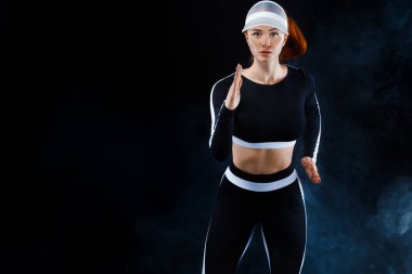 Güçlü bir atletik, siyah arka planda koşan, dar ve formalı bir bayan..