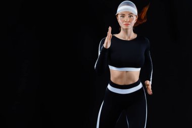 Güçlü bir atletik, siyah arka planda koşan, dar ve formalı bir bayan..
