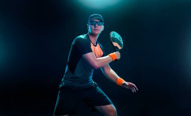 Raketli bir plaj tenisçisi. Siyah arka planda tek başına oynayan erkek sporcu