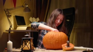 Illuminating pumpkin for Halloween. Woman sitting, lighting and showing out candle lit halloween Jack O Lantern pumpkin at home for her family.