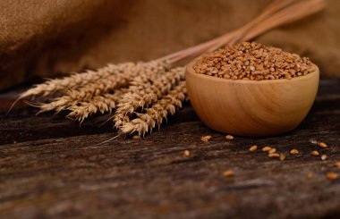 Buğday ve buğday taneleri kahverengi ahşap zemin üzerinde kase