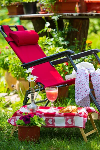 stock image A sun lounger for relaxing and a table with food stands in the garden on green grass