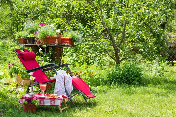 stock image A sun lounger for relaxing and a table with food stands in the garden on green grass