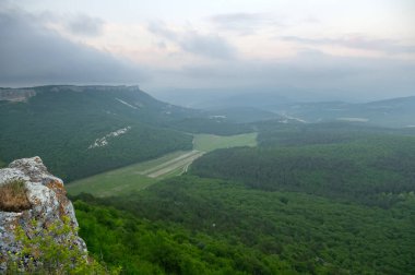 Dağ sırasının yüksekliğinden dağ manzarası. Yeşil çayırlarla kaplı dağların üzerinde mavi yaz gökyüzü.