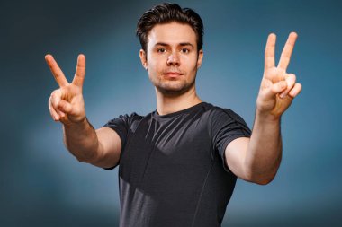 Young brunette man showing victory handsign