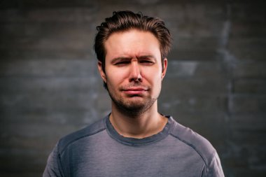 Young handsome man crying portrait on gray wall background