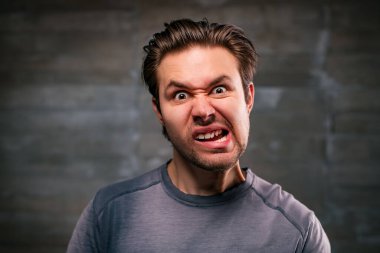 Young crazy man emotional portrait on gray wall background
