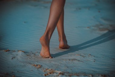 Young woman walk barefoot on sand at evening