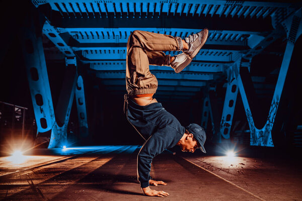 Молодой крутой танцор, позирующий на городском мосту ночью