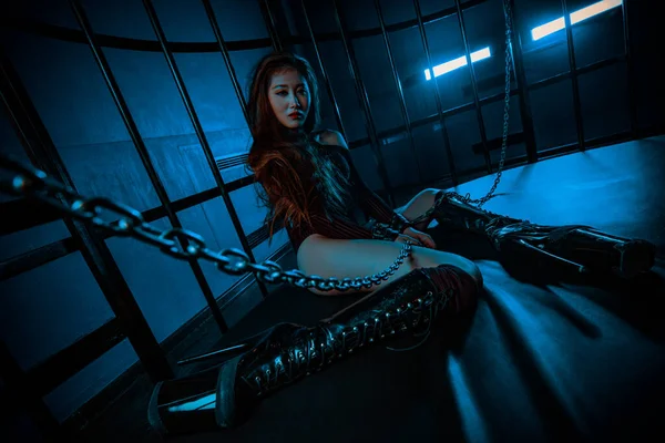 Young asian woman sitting in cage with chains bdsm style portrait