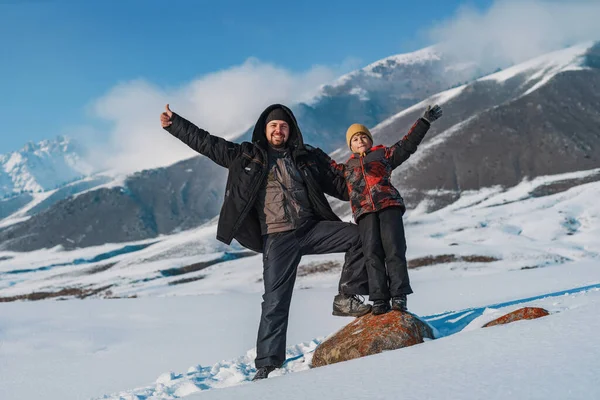快乐的父亲和孩子们挥手站在高山的背景上过冬 — 图库照片
