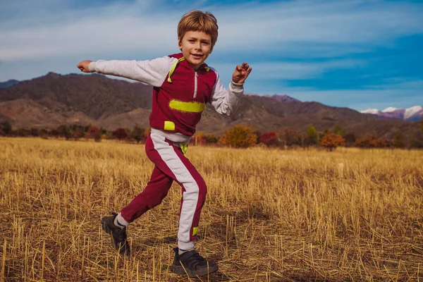 孩子们在秋天的田野上跑着 背景是高山 — 图库照片