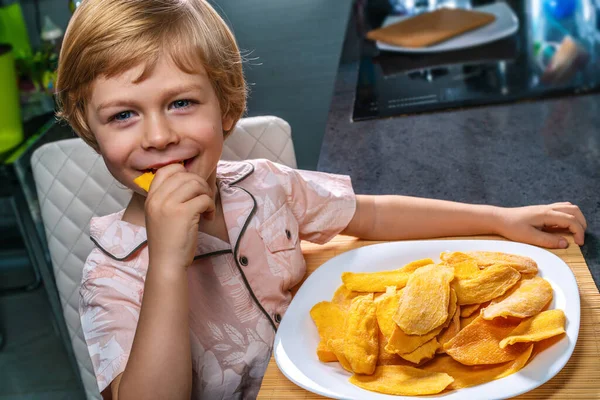 Uśmiechnięte Dziecko Jedzące Suszone Mango Kuchni — Zdjęcie stockowe