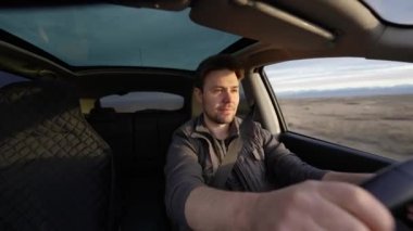 Güneşli bir günde arabayı off-road yapan bir adam iç görünüşte
