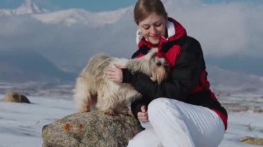 Kış dağlarında köpeği olan genç bir turist kadın.