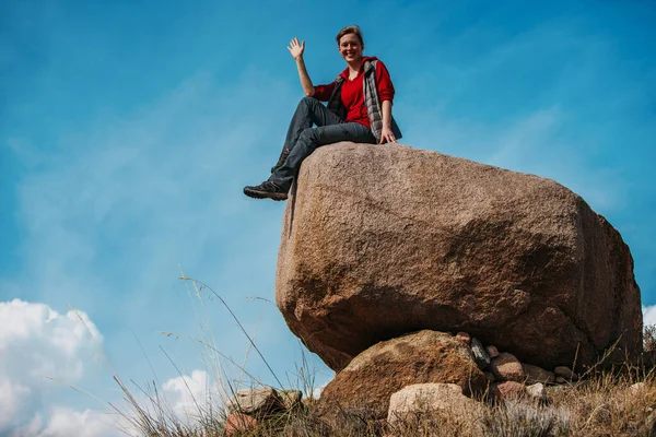 Νεαρή Τουρίστρια Κάθεται Ένα Μεγάλο Βράχο Και Κουνάει Χέρι Της — Φωτογραφία Αρχείου