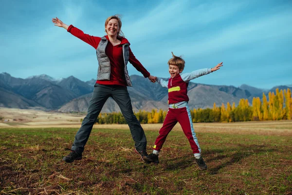 幸せな母親と息子の山の背景にジャンプ — ストック写真