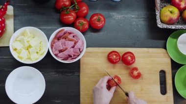 Mutfakta yemek pişiren, güvertede domates kesen bir kadın.