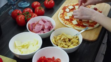 Kadın evde sosisli ve mantarlı pizza yapıyor.