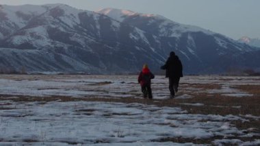 Baba ve oğul kışın dağlarda koşar alacakaranlıkta