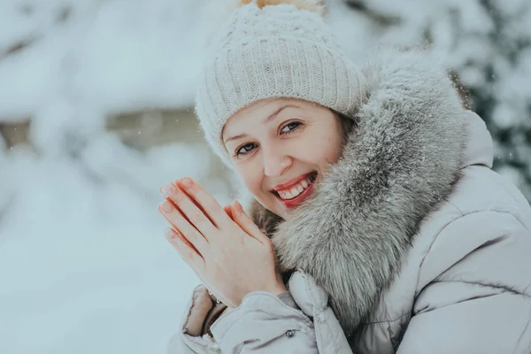 穿着温暖冬衣的年轻女子试图用她冰冷的手取暖 — 图库照片