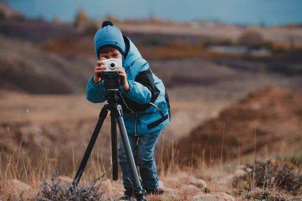 男孩带着相机在山中三脚架上拍照 — 图库照片