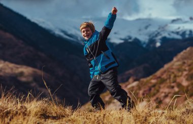 Sonbaharda dağların arka planında başarılı bir çocuk