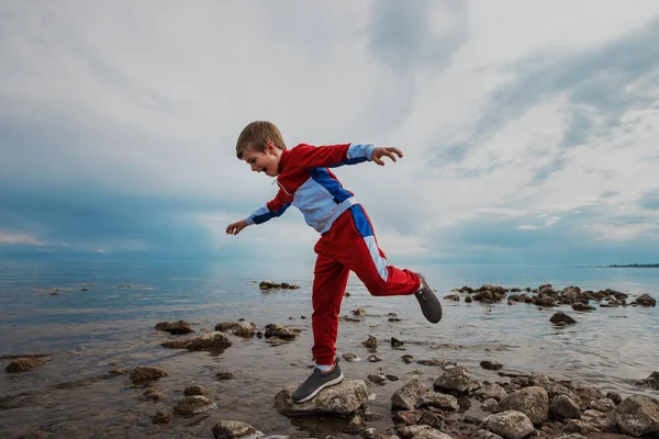 男孩在湖岸的岩石上保持平衡 — 图库照片