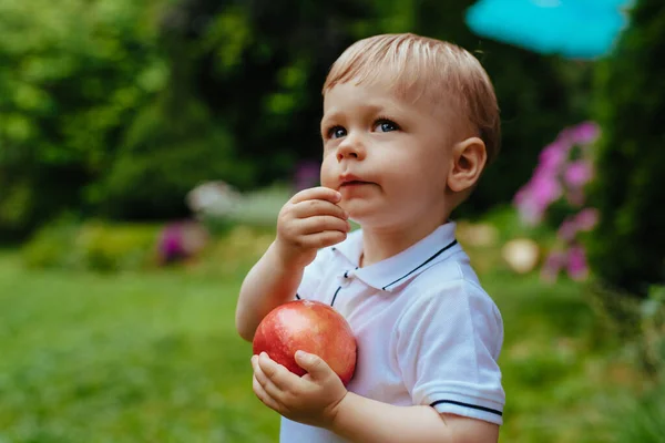 庭に大きな赤いリンゴを持つ1歳の子供 — ストック写真
