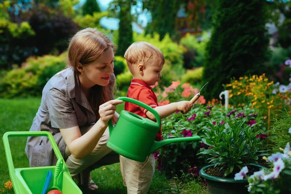 一位年轻的妇女和她一岁的孩子在花园里种花 — 图库照片